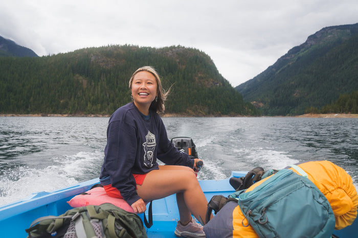 Woman driving a boat with camping and hiking gear
