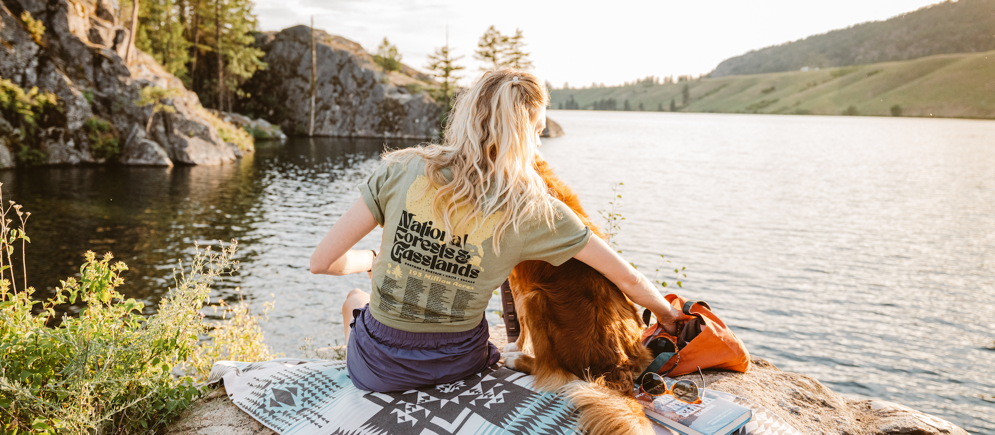 girl sitting next to lake with dog. 