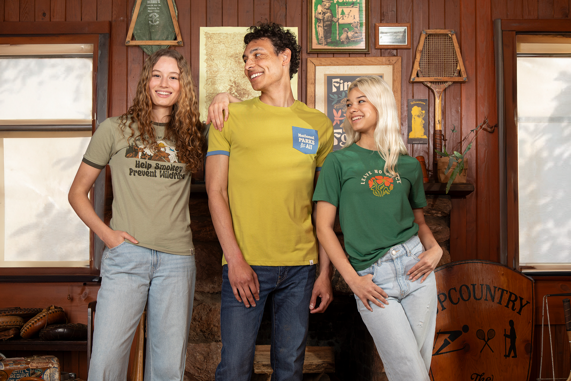 3 young adults standing in a cabin wearing stylish graphic t-shirts.